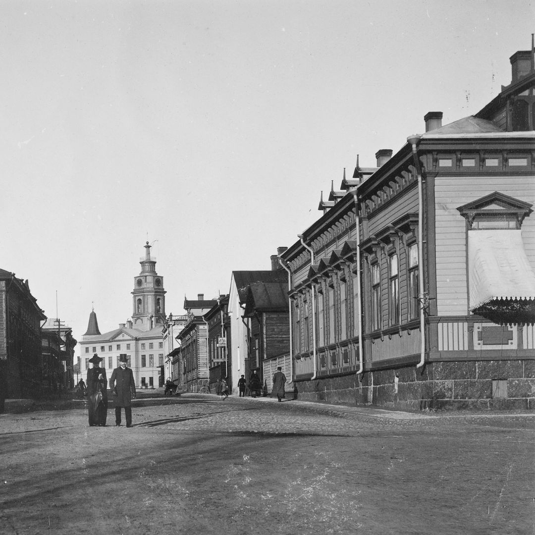 1890-luvulla valokuvattu katukuva Haminan Raatihuoneelle päin. Keskellä katua seisoo mies ja nainen kohti kameraa.